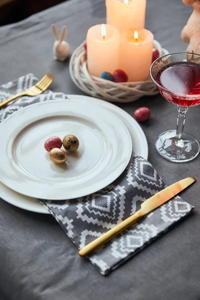 Selective focus of plates with cloth napkin, eggs in basket, wine in crystal glass on table at home — Stock Photo