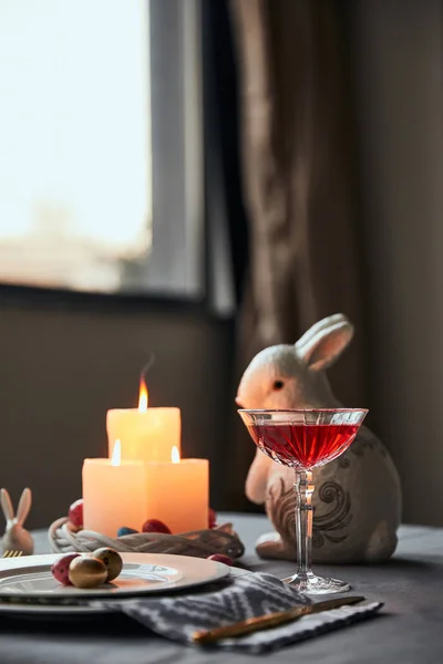 Messa a fuoco selettiva di piatti con uova, vino in cristallo e coniglio decorativo in tavola a casa — Foto stock