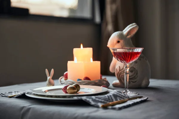 Selective focus of plates with eggs, wine in crystal glass, burning candles and decorative rabbit on table at home — Stock Photo