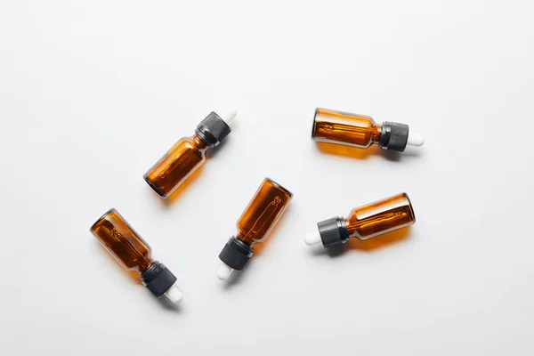 Vista superior de botellas marrones con aceite esencial sobre superficie gris - foto de stock