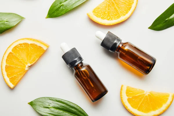 Top view of essential oil and orange slices on grey background — Stock Photo