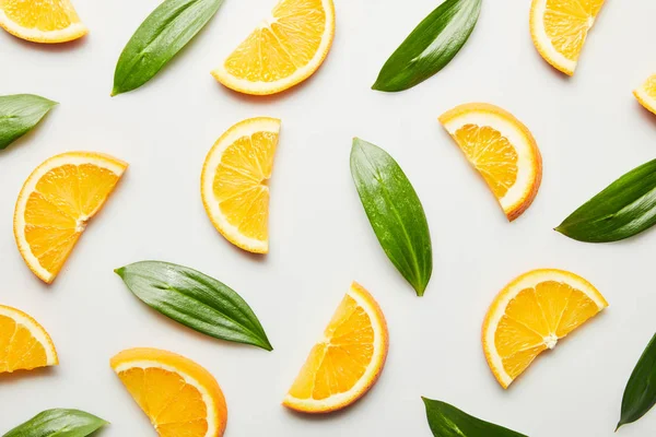 Ansicht von Orangenscheiben und grünen Blättern auf weißem Hintergrund — Stockfoto