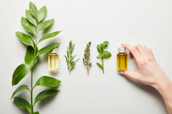 Partial view of woman holding bottle with essential oil on white background — Stock Photo