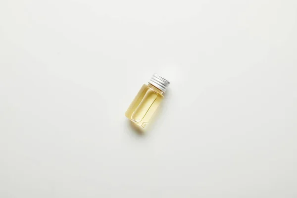 Vista superior del aceite esencial en botella sobre superficie blanca - foto de stock