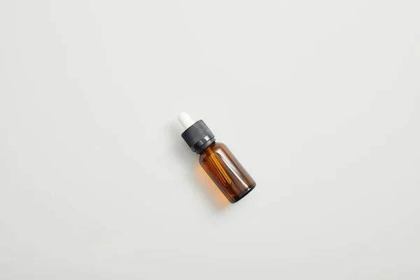 Top view of brown bottle with essential oil on grey background — Stock Photo