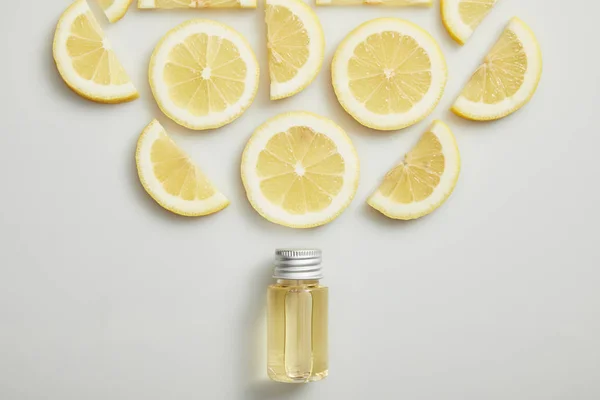 Flat lay with essential oil and cut lemon on grey background — Stock Photo