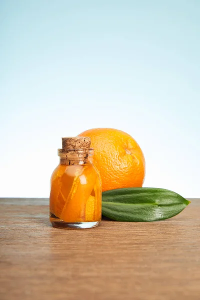 Ripe orange and glass bottle standing on wooden surface — Stock Photo