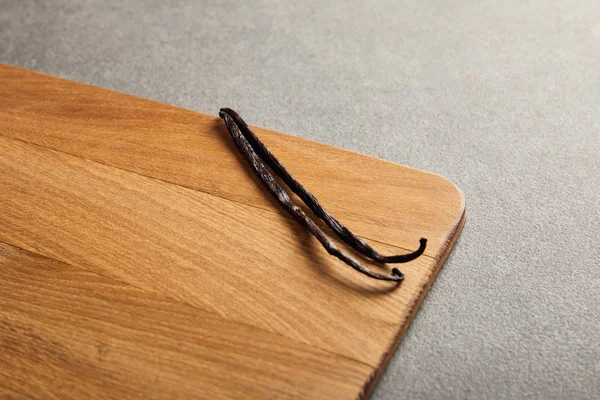 Vainas de vainilla acostado sobre tabla de cortar de madera en la superficie oscura — Stock Photo