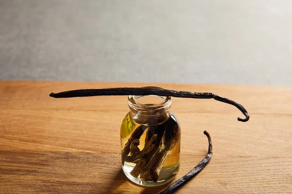 Bottiglia di olio essenziale con baccelli di vaniglia su superficie di legno — Foto stock
