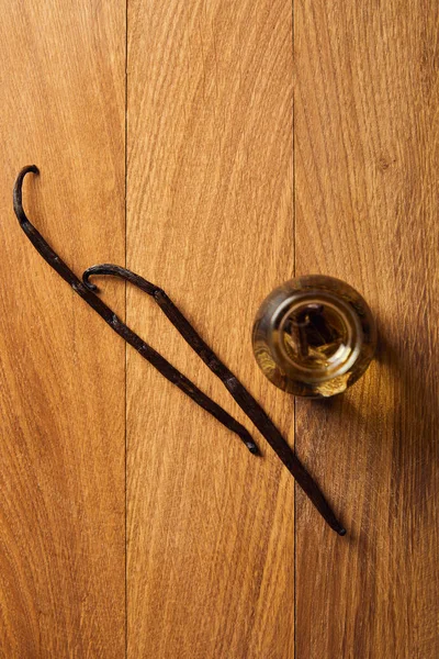 Vue de dessus de l'huile essentielle avec gousses de vanille sur la surface en bois — Photo de stock