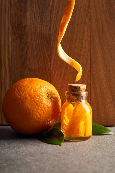Óleo essencial laranja e orgânico em garrafa de vidro sobre fundo de madeira — Fotografia de Stock