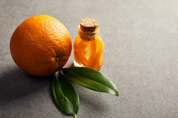 Fresh whole orange with essential oil on dark surface — Stock Photo