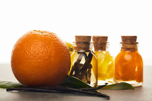Botellas de aceite esencial con naranja y vainilla sobre fondo blanco - foto de stock
