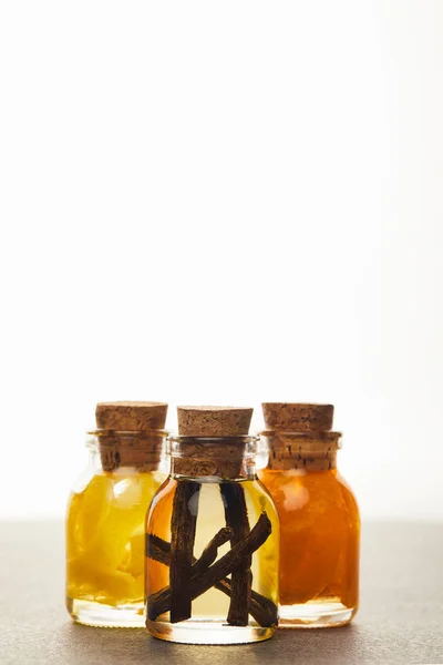 Glass bottles of essential oil with cut fruits on white background — Stock Photo