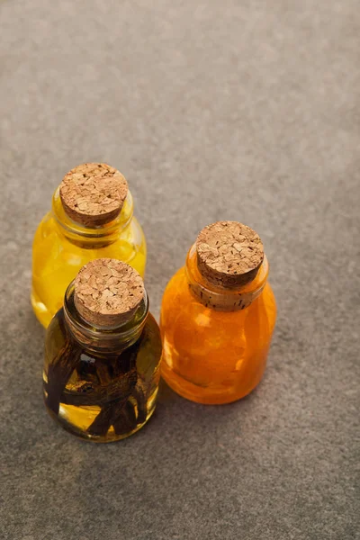 Vista superior de garrafas de vidro com óleo essencial orgânico na superfície escura — Fotografia de Stock
