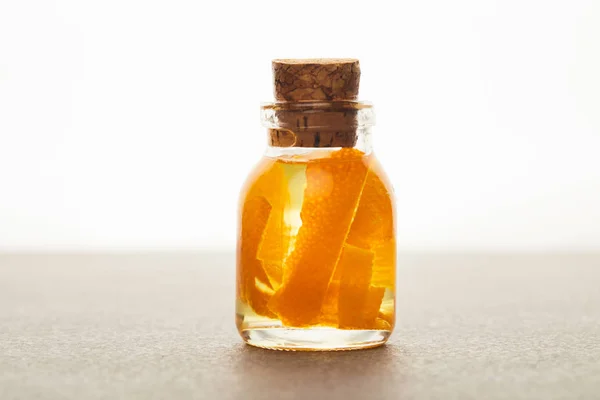 Botella de vidrio de aceite esencial con naranja cortada sobre fondo blanco - foto de stock