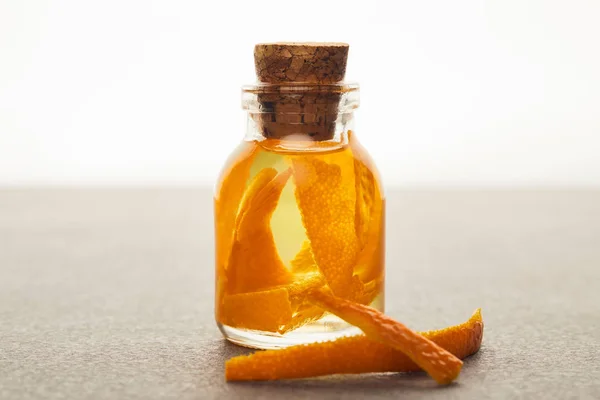 Стеклянная бутылка органического эфирного масла с оранжевыми кусочками на белом фоне — стоковое фото