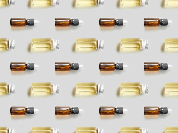 Flat lay with glass bottles of essential oil on grey background — Stock Photo