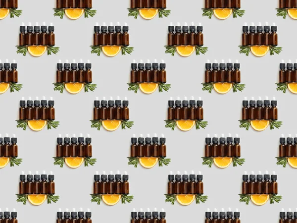 Vista superior de garrafas de vidro com óleo essencial e fatia de laranja em cinza — Fotografia de Stock