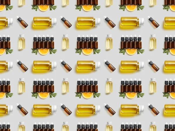 Pattern with various bottles with essential oil and sliced orange on grey background — Stock Photo