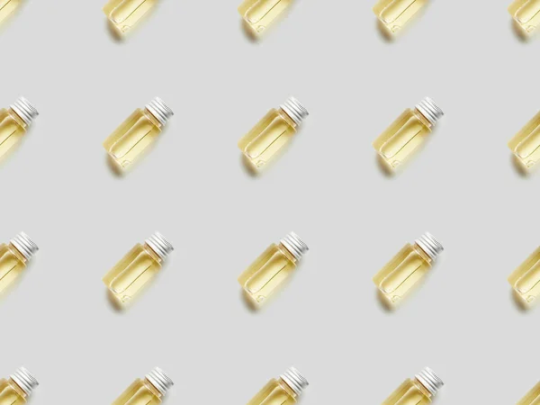 Pattern with essential oil in glass bottles on grey — Stock Photo