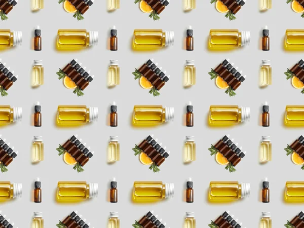 Motif avec des bouteilles d'huile essentielle bio et d'orange tranchée sur gris — Photo de stock