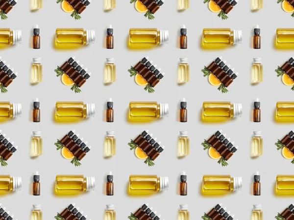 Pattern with bottles of organic essential oil and sliced orange on grey — Stock Photo