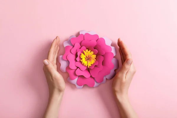 Vista recortada de la mujer con flor de papel sobre fondo rosa - foto de stock