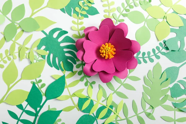 Top view of pink paper flower and green leaves on white background — Stock Photo