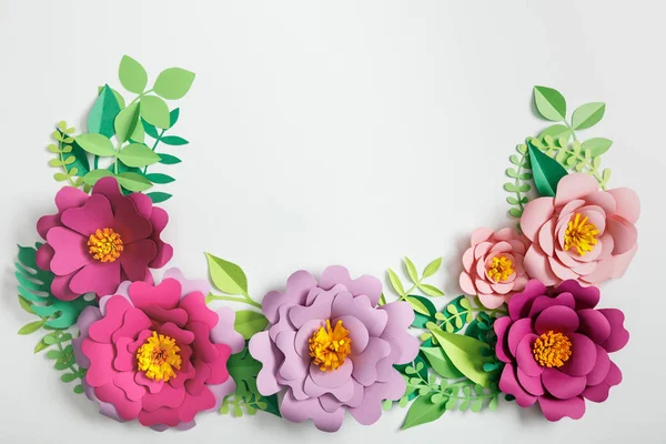 Верхний вид розовых и лиловых бумажных цветов и зеленых растений с листьями на сером фоне — стоковое фото