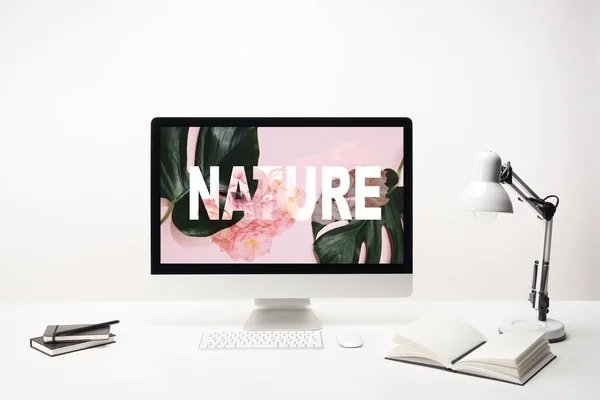 Computer con scritte naturali e foglie tropicali verdi e rose sul monitor sulla scrivania su sfondo bianco — Foto stock