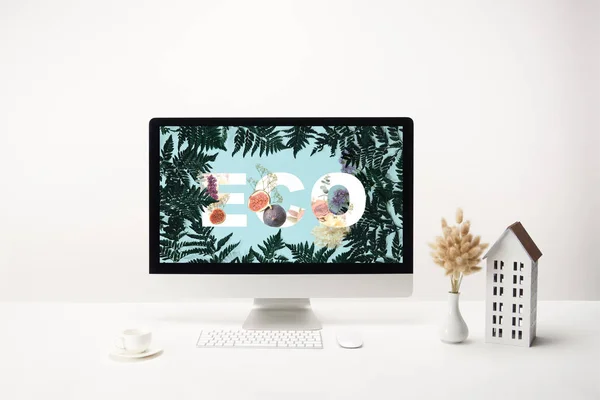 Computer con scritte ecologiche su monitor e decorazione con tazza di caffè su scrivania su sfondo bianco — Foto stock