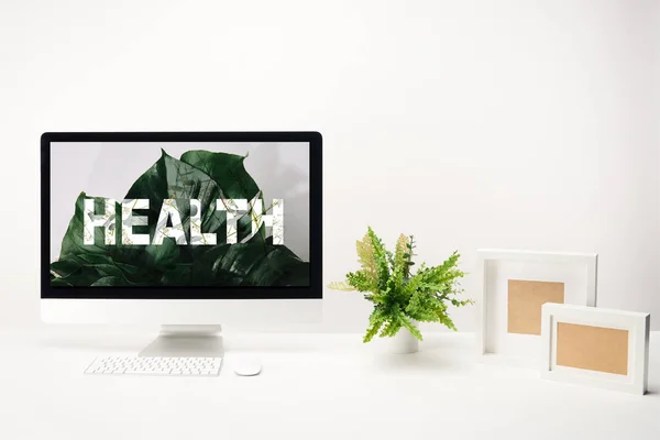 Ordenador con letras de salud en el monitor sobre fondo blanco - foto de stock