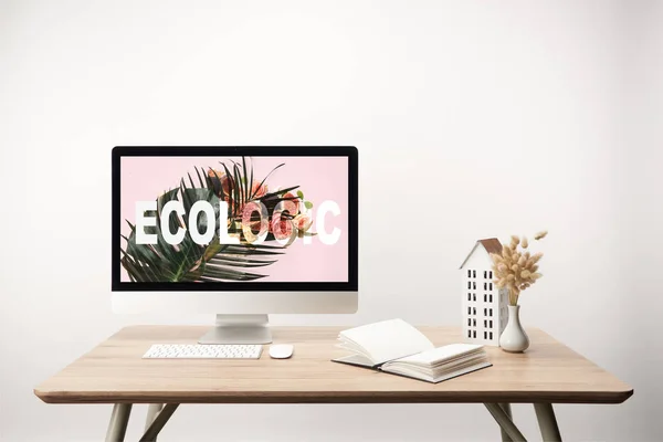 Computer mit grünem Blatt und ökologischem Schriftzug auf Monitor auf Holztisch — Stockfoto