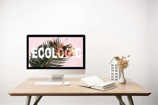 Computadora con hoja verde y letras ecológicas en monitor en escritorio de madera - foto de stock