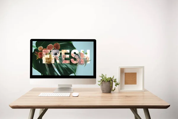 Computer with green leaves and fresh illustration on monitor on wooden desk — Stock Photo