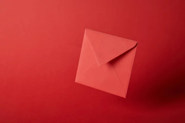 Яскравий, барвистий і порожній конверт на червоному тлі з простором для копіювання — стокове фото