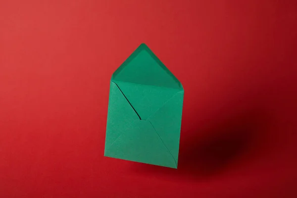Яркий, пустой и зеленый конверт на красном фоне с копировальным пространством — стоковое фото