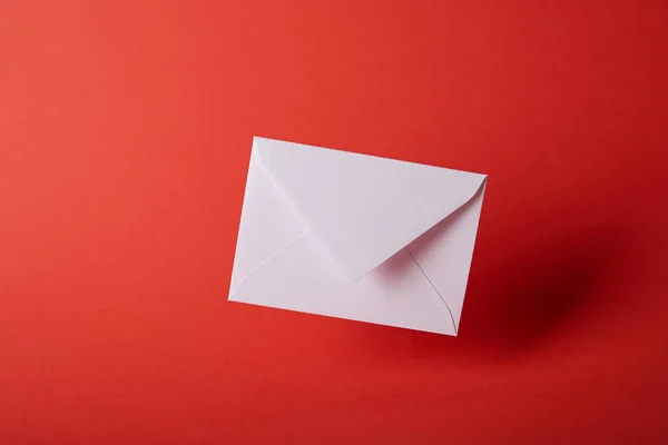Белый и пустой конверт на красном фоне с копировальным пространством — стоковое фото