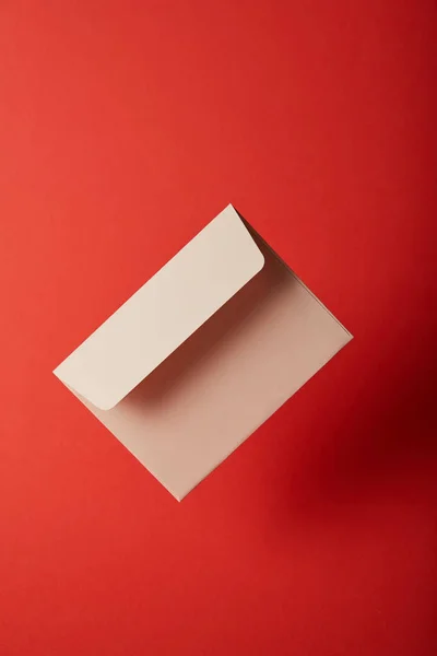 Бежевий, порожній і порожній конверт на червоному тлі з пробілом для копіювання — стокове фото