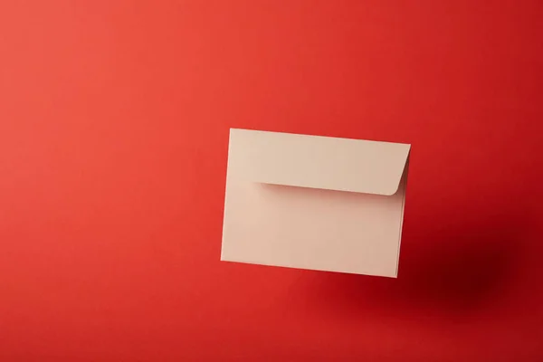 Beige, blank and empty envelope on bright red background with copy space — Stock Photo