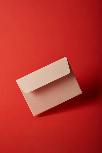 Envelope bege, em branco e vazio no fundo vermelho colorido brilhante com espaço de cópia — Fotografia de Stock