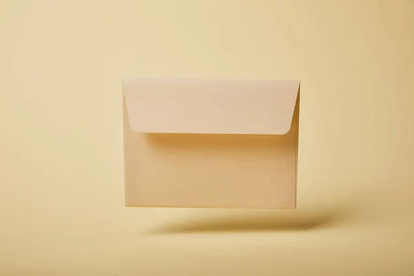 Envelope bege e pastel em fundo amarelo com espaço de cópia — Fotografia de Stock