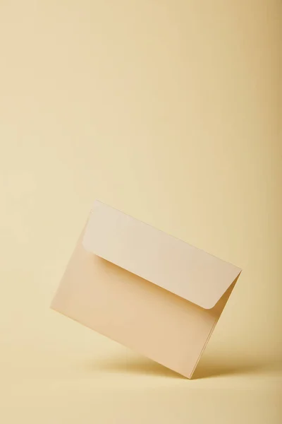 Beige and empty envelope on yellow background with copy space — Stock Photo