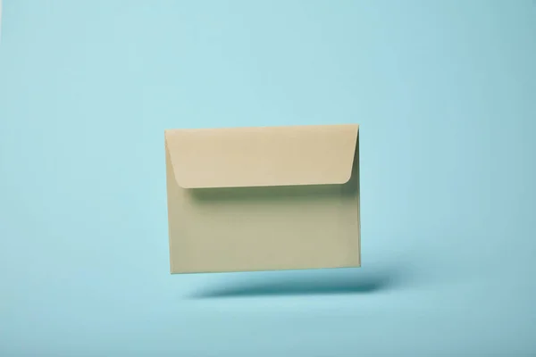 Beige and empty envelope on blue background with copy space — Stock Photo