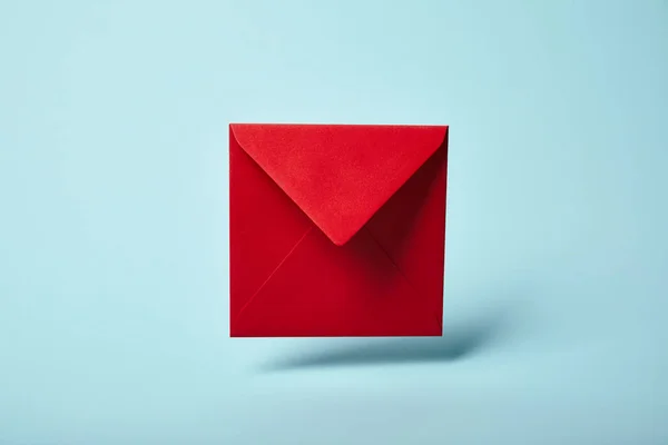 Красный и яркий конверт на синем фоне с копировальным пространством — стоковое фото