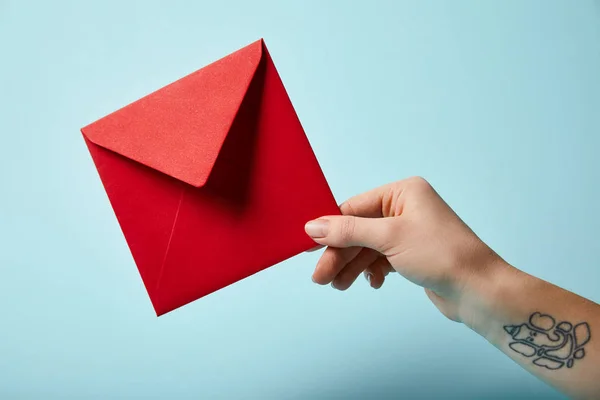 Teilansicht einer tätowierten Frau mit rotem Umschlag auf blauem Hintergrund — Stockfoto
