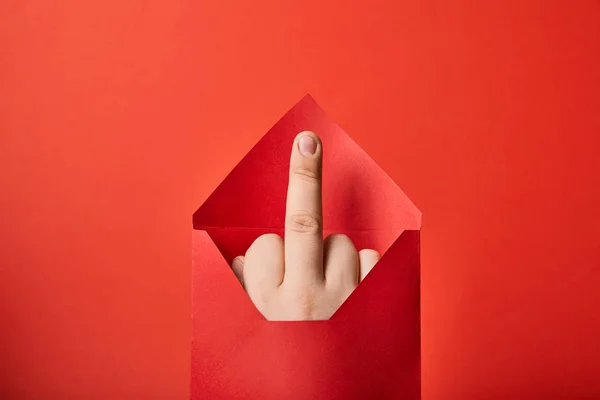 Vue partielle de l'homme montrant le majeur dans une enveloppe lumineuse sur fond rouge — Photo de stock