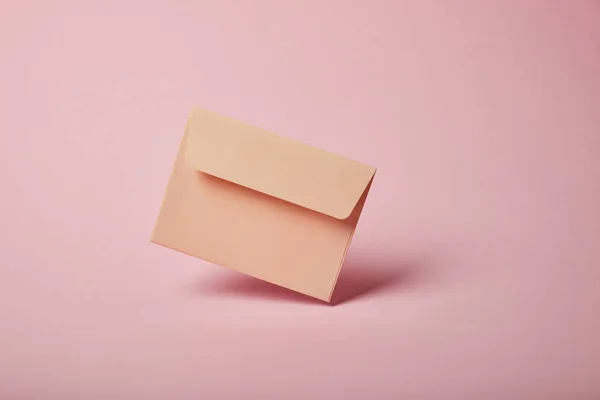 Beige and empty envelope on pink background with copy space — Stock Photo