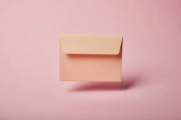 Beige and empty envelope on pink background with copy space — Stock Photo